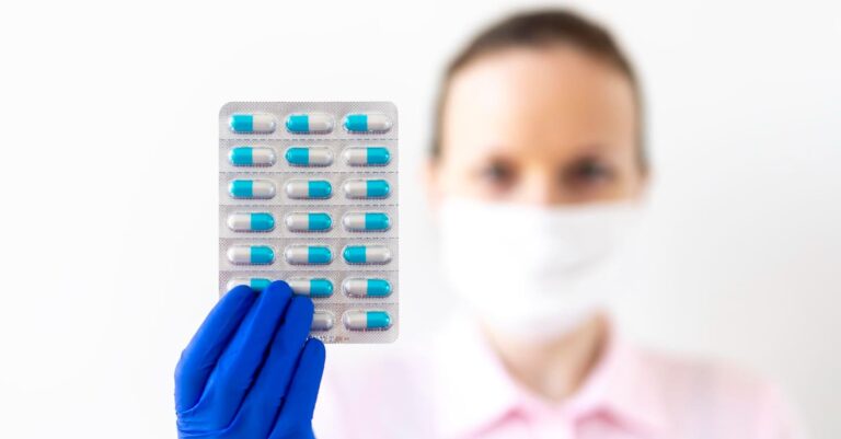 Mulher com uma luva médica de borracha azul segura uma cartela de importadora de medicamentos