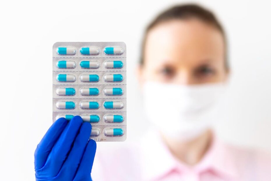 Mulher com uma luva médica de borracha azul segura uma cartela de importadora de medicamentos